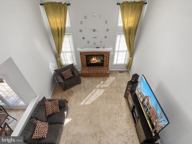 living room with a brick fireplace, carpet, baseboards, and a towering ceiling