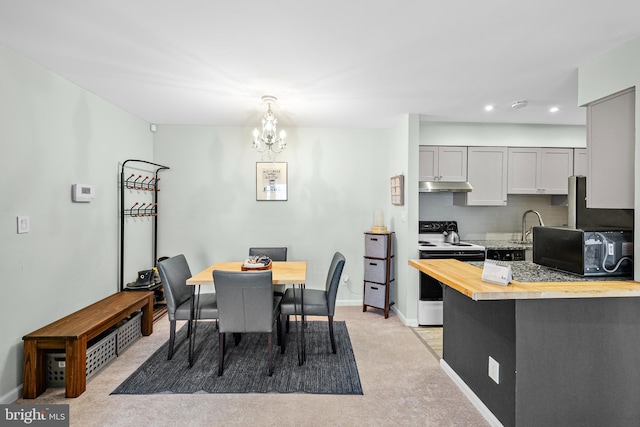 carpeted dining room featuring sink and a chandelier