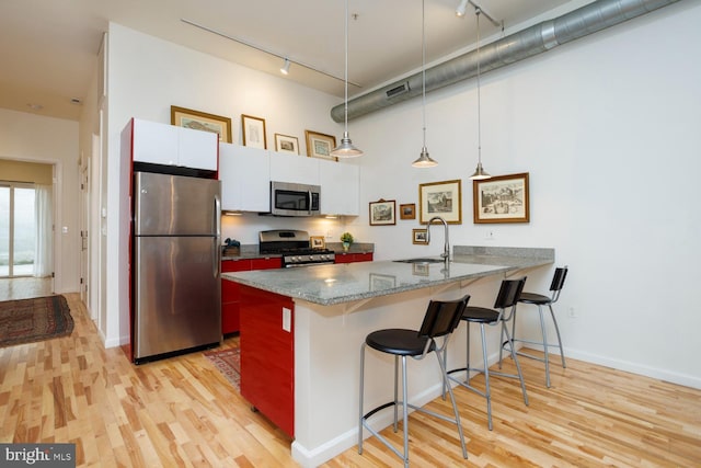 kitchen featuring pendant lighting, sink, a breakfast bar area, appliances with stainless steel finishes, and white cabinetry