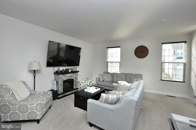 carpeted living room with a stone fireplace