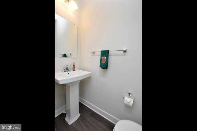 bathroom with hardwood / wood-style flooring, toilet, and sink