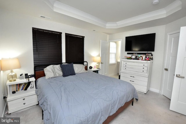 bedroom with a tray ceiling and light colored carpet