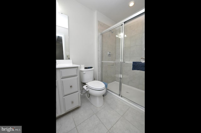 bathroom featuring a shower with door, vanity, tile patterned floors, and toilet