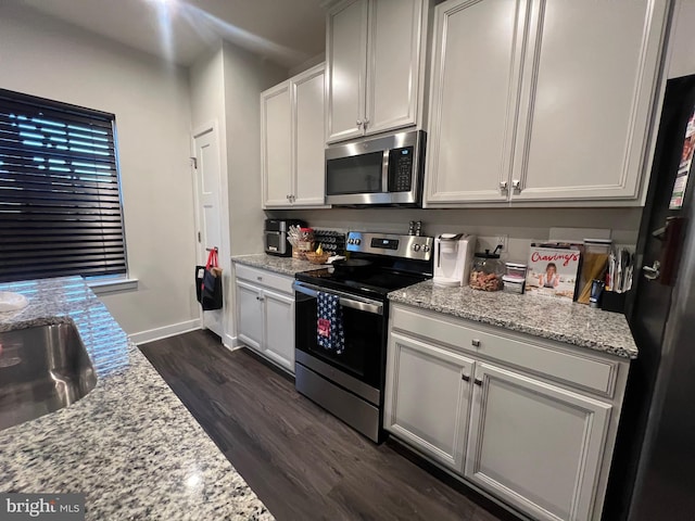 kitchen with dark wood-type flooring, sink, light stone counters, white cabinetry, and stainless steel appliances