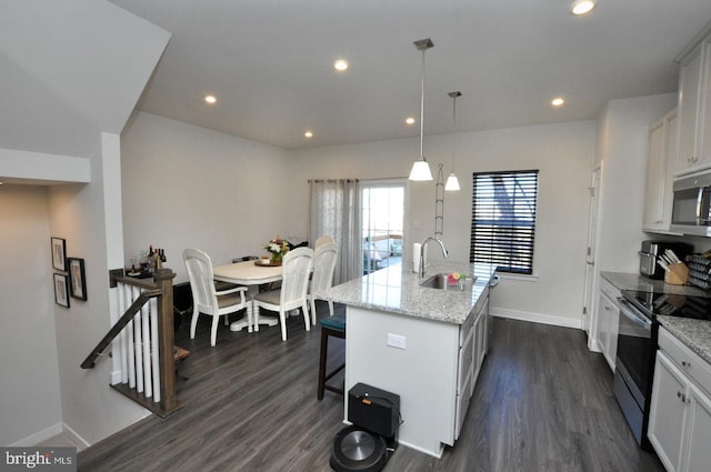 kitchen with pendant lighting, light stone counters, stainless steel appliances, and a center island with sink