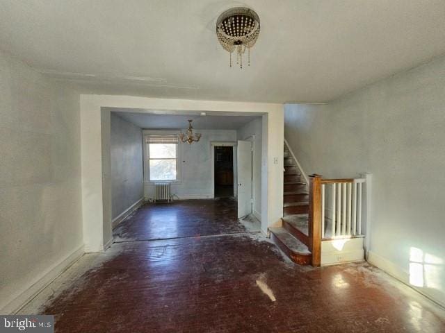 unfurnished room with radiator heating unit and a chandelier