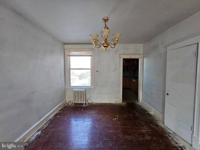 empty room featuring radiator heating unit and a notable chandelier