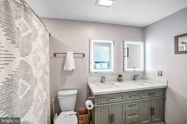 bathroom featuring vanity, a textured ceiling, curtained shower, and toilet