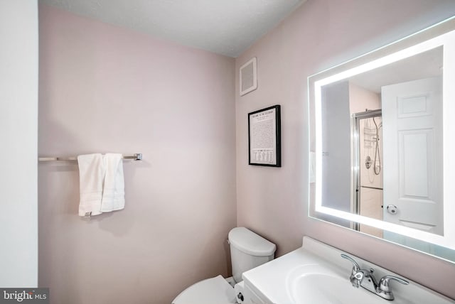 bathroom with vanity, a shower with door, and toilet