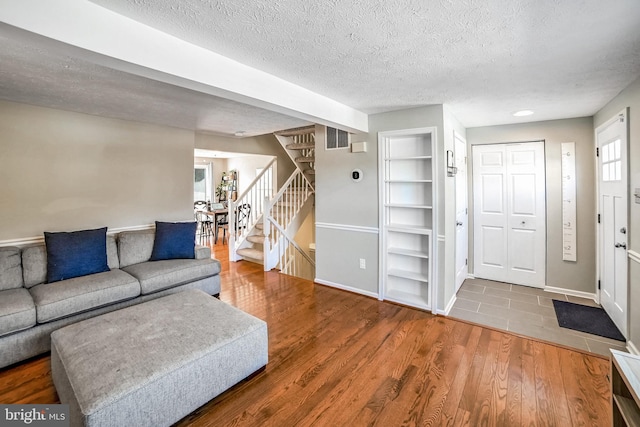 living room with built in features, hardwood / wood-style floors, and a textured ceiling