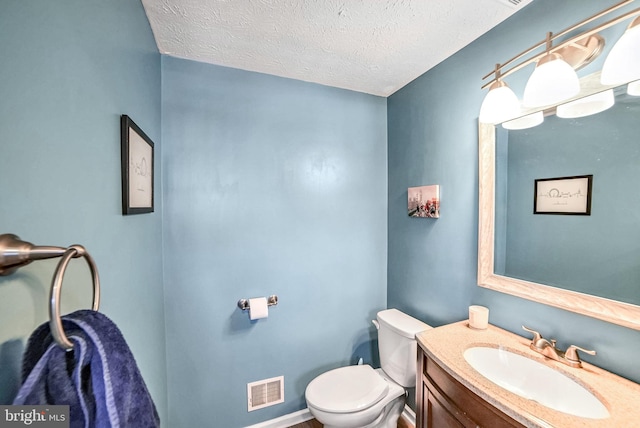 bathroom featuring vanity, a textured ceiling, and toilet