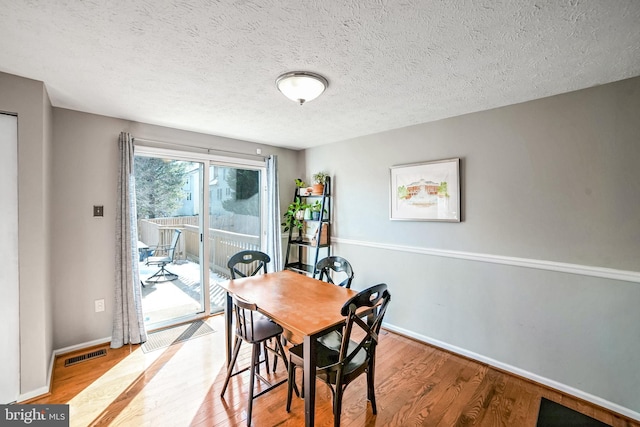 dining space featuring light hardwood / wood-style floors and a textured ceiling