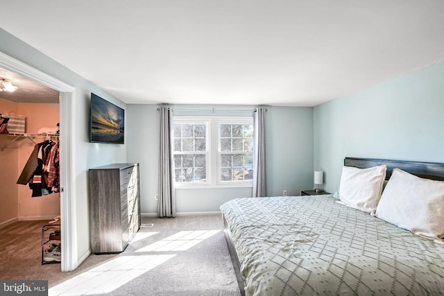 bedroom with light carpet, a walk in closet, and a closet