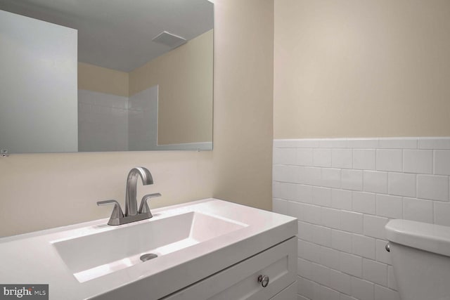 bathroom with vanity, tile walls, and toilet