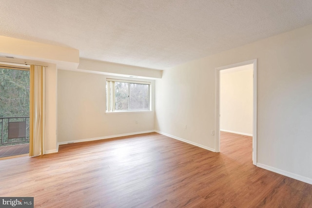 spare room with light hardwood / wood-style flooring and a textured ceiling