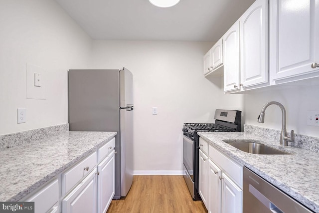 kitchen featuring light stone counters, stainless steel appliances, sink, and white cabinets