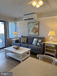 living room featuring an AC wall unit, dark hardwood / wood-style floors, and ceiling fan