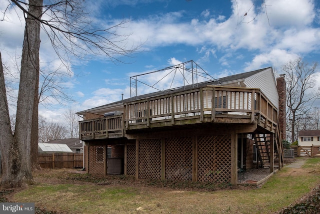 rear view of house featuring a deck, stairway, fence, and a chimney