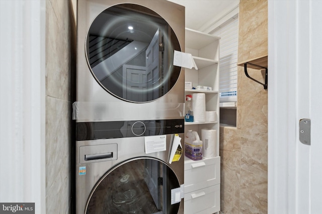 clothes washing area with tile walls and stacked washing maching and dryer