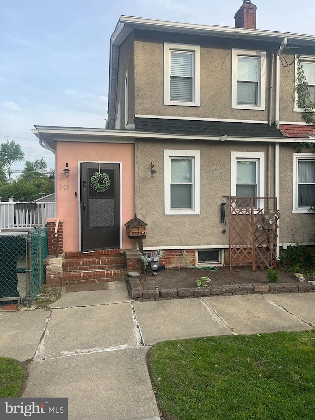 348 Broad St, Mount Holly, NJ 08060 - townhome / multi-family property featuring stucco siding, entry steps, fence, and a chimney