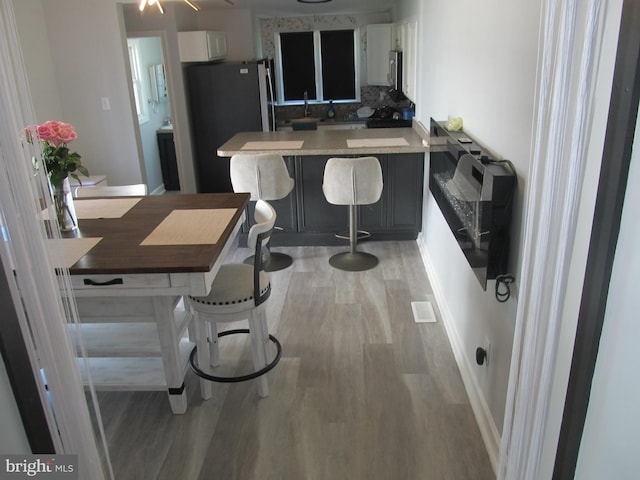 348 Broad St, Mount Holly, NJ 08060 - kitchen with light wood-type flooring, a peninsula, tasteful backsplash, stainless steel appliances, and white cabinetry