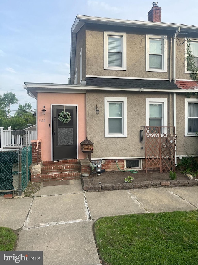 348 Broad St, Mount Holly, NJ 08060 - view of front facade with stucco siding, entry steps, fence, and a chimney