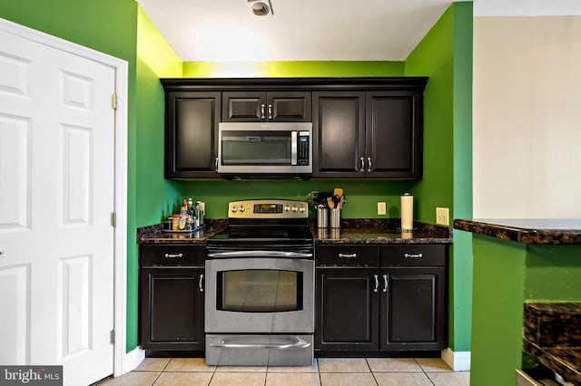 kitchen featuring visible vents, dark stone counters, appliances with stainless steel finishes, light tile patterned floors, and baseboards