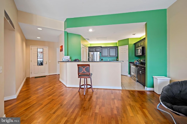 kitchen featuring open floor plan, appliances with stainless steel finishes, light wood-style floors, and a peninsula