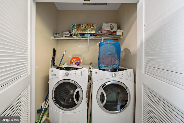 clothes washing area with laundry area, visible vents, and washer and clothes dryer