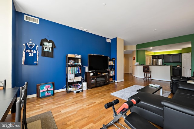 living area with visible vents, baseboards, and wood finished floors