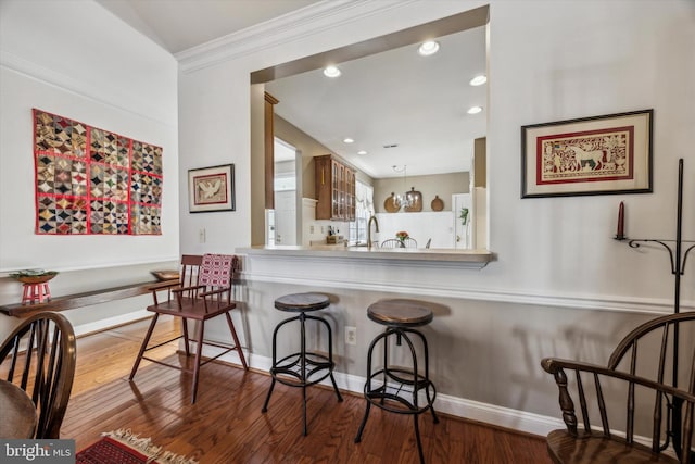 kitchen with ornamental molding, wood-type flooring, and sink