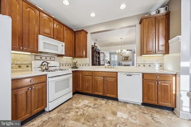 kitchen featuring sink, white appliances, hanging light fixtures, a notable chandelier, and decorative backsplash