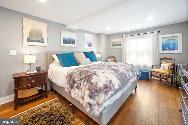 bedroom featuring beam ceiling and dark hardwood / wood-style flooring