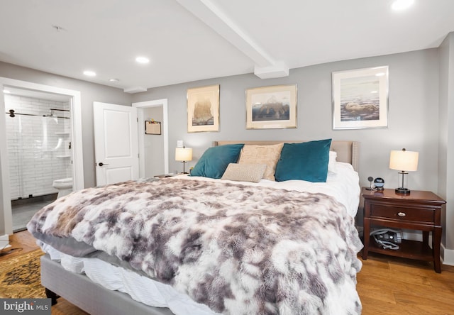 bedroom with beam ceiling, connected bathroom, and light wood-type flooring