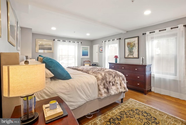 bedroom featuring beam ceiling and light hardwood / wood-style floors