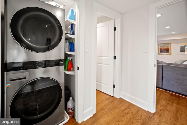 laundry area with stacked washing maching and dryer and light wood-type flooring