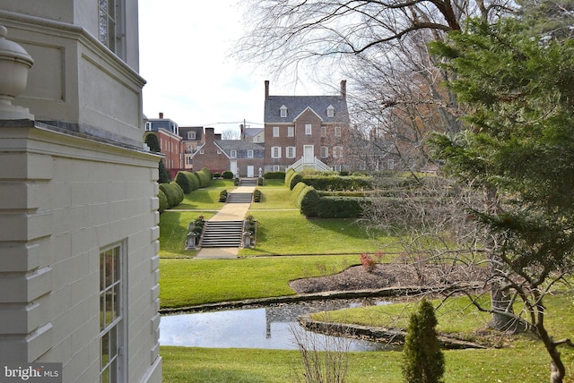 surrounding community with a water view and a lawn