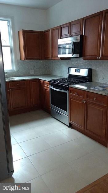 kitchen featuring appliances with stainless steel finishes, decorative backsplash, and light tile patterned floors