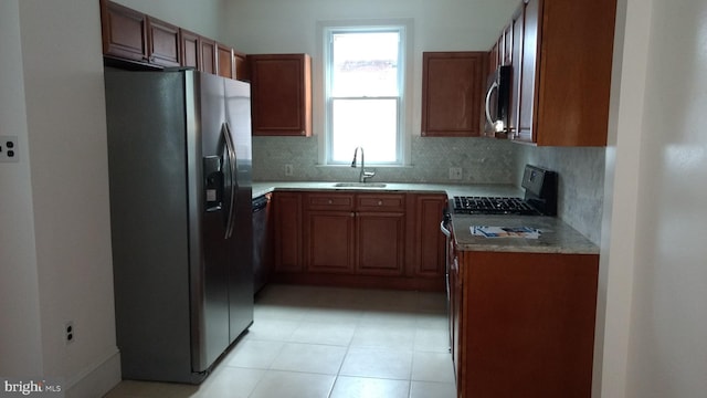 kitchen with stainless steel appliances, sink, light tile patterned floors, and backsplash