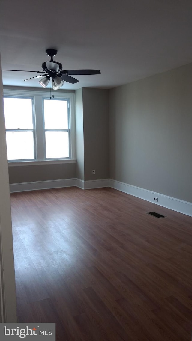 empty room with dark wood-type flooring and ceiling fan