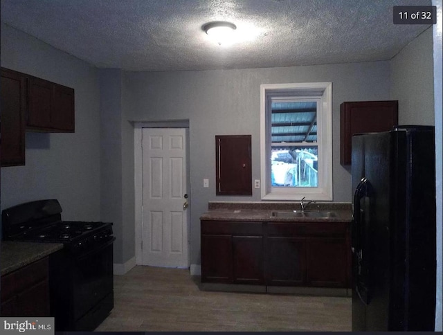 kitchen featuring sink, light hardwood / wood-style flooring, dark brown cabinetry, black appliances, and a textured ceiling