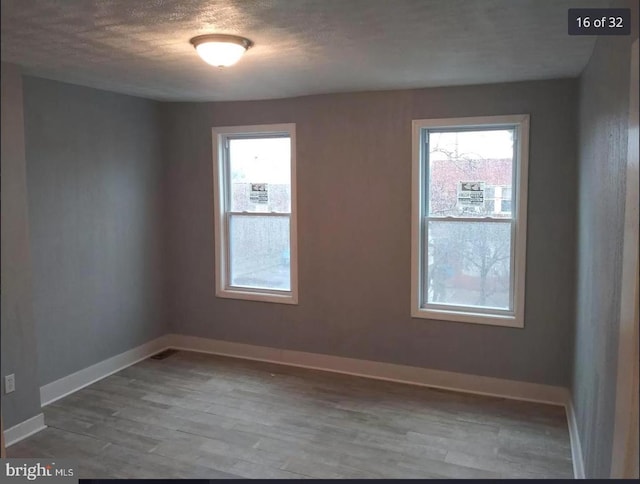 unfurnished room featuring wood-type flooring, plenty of natural light, and a textured ceiling