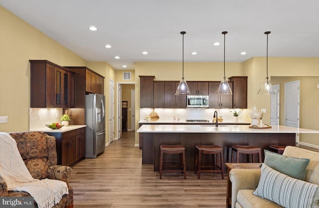 kitchen with dark brown cabinetry, hanging light fixtures, stainless steel appliances, and sink