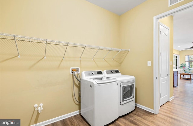 clothes washing area with hardwood / wood-style flooring and washer and dryer