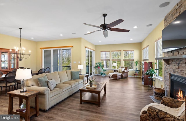 living room with dark wood-type flooring, ceiling fan with notable chandelier, and a fireplace