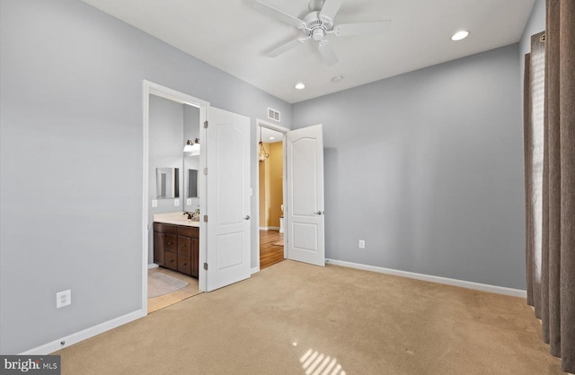 unfurnished bedroom featuring connected bathroom, sink, and light carpet