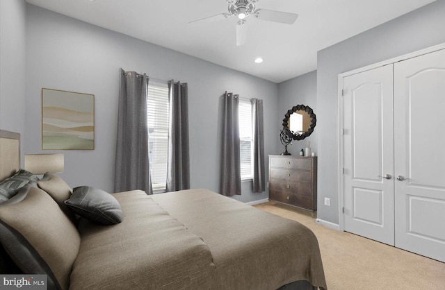 bedroom featuring light colored carpet, a closet, and ceiling fan