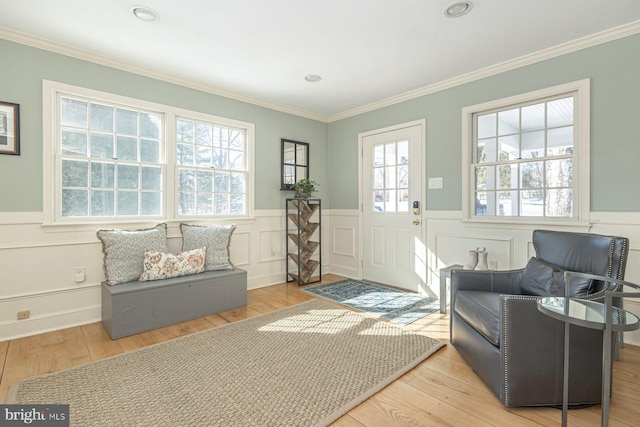 living area with crown molding, a healthy amount of sunlight, and light wood-type flooring