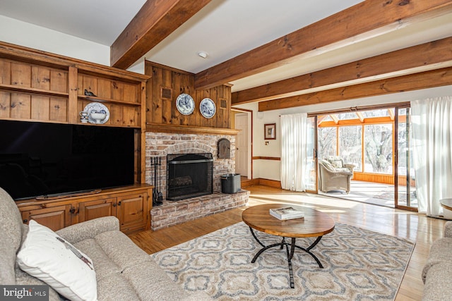 living room featuring a brick fireplace, wooden walls, light hardwood / wood-style floors, and beamed ceiling