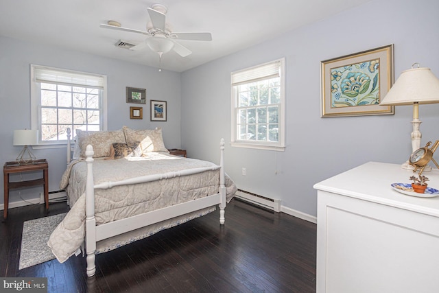 bedroom featuring ceiling fan, dark hardwood / wood-style flooring, multiple windows, and a baseboard heating unit